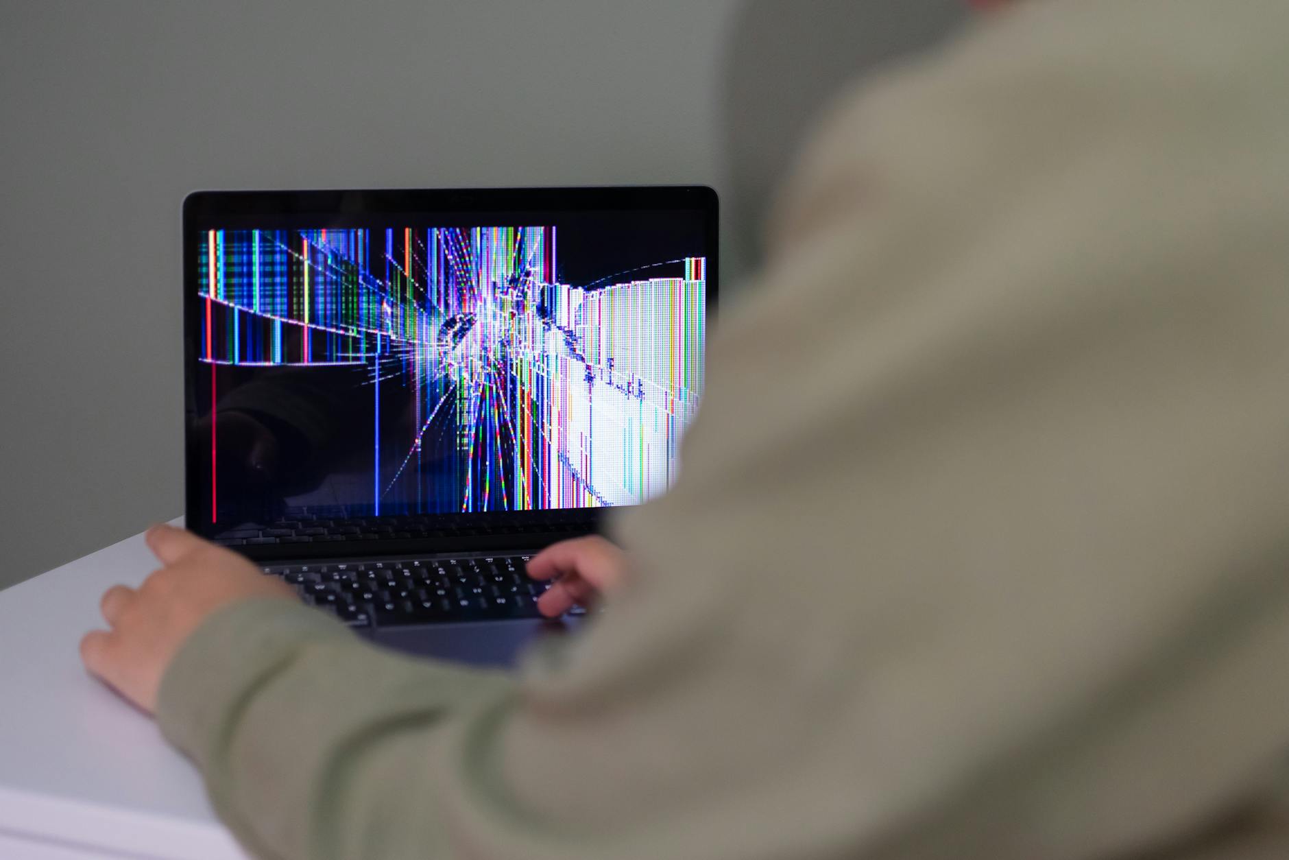 Osoba korzysta z laptopa Toshiba z pękniętym, zniekształconym ekranem