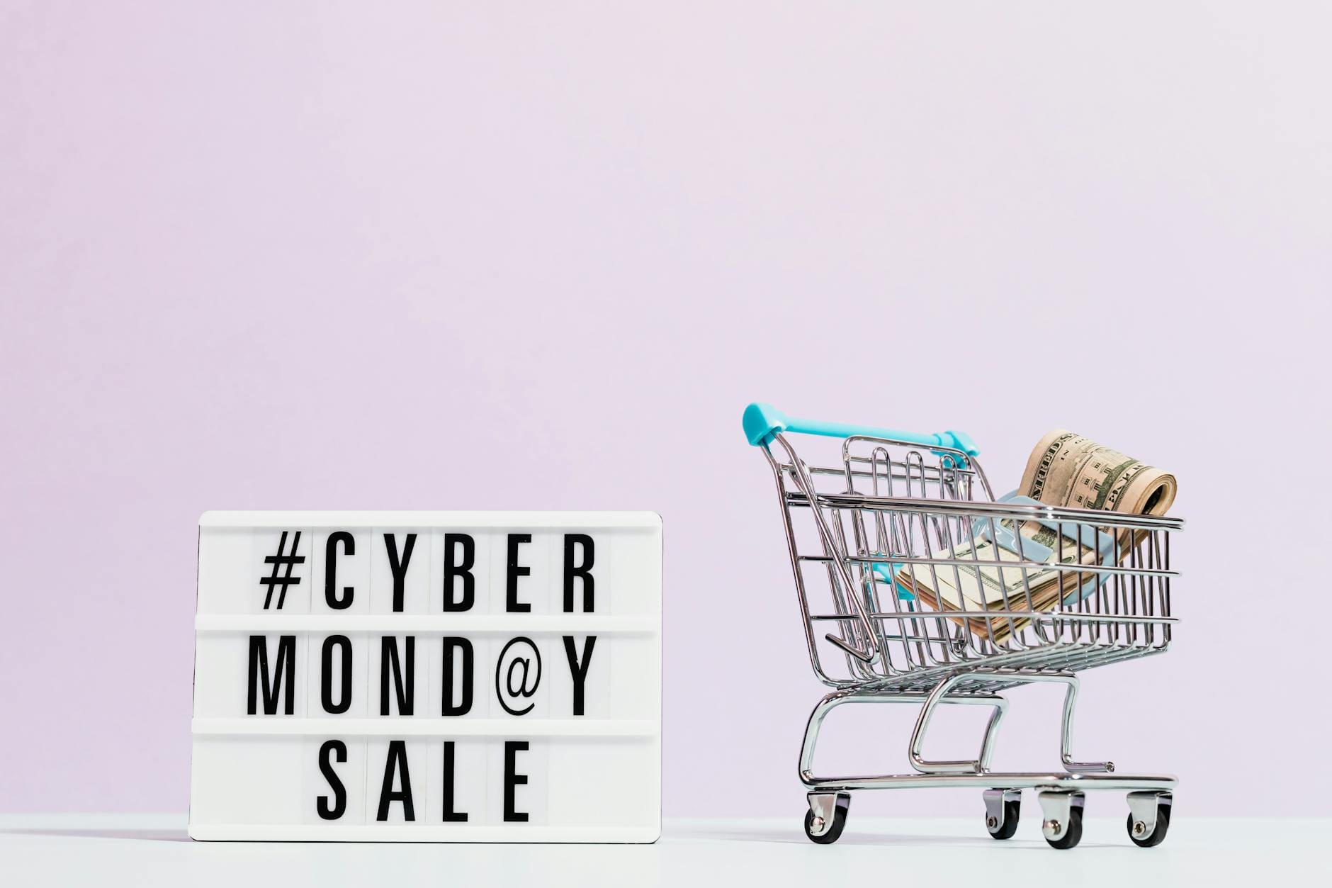 Wózek sklepowy pełen gotówki obok plakatu promocji Cyber Monday