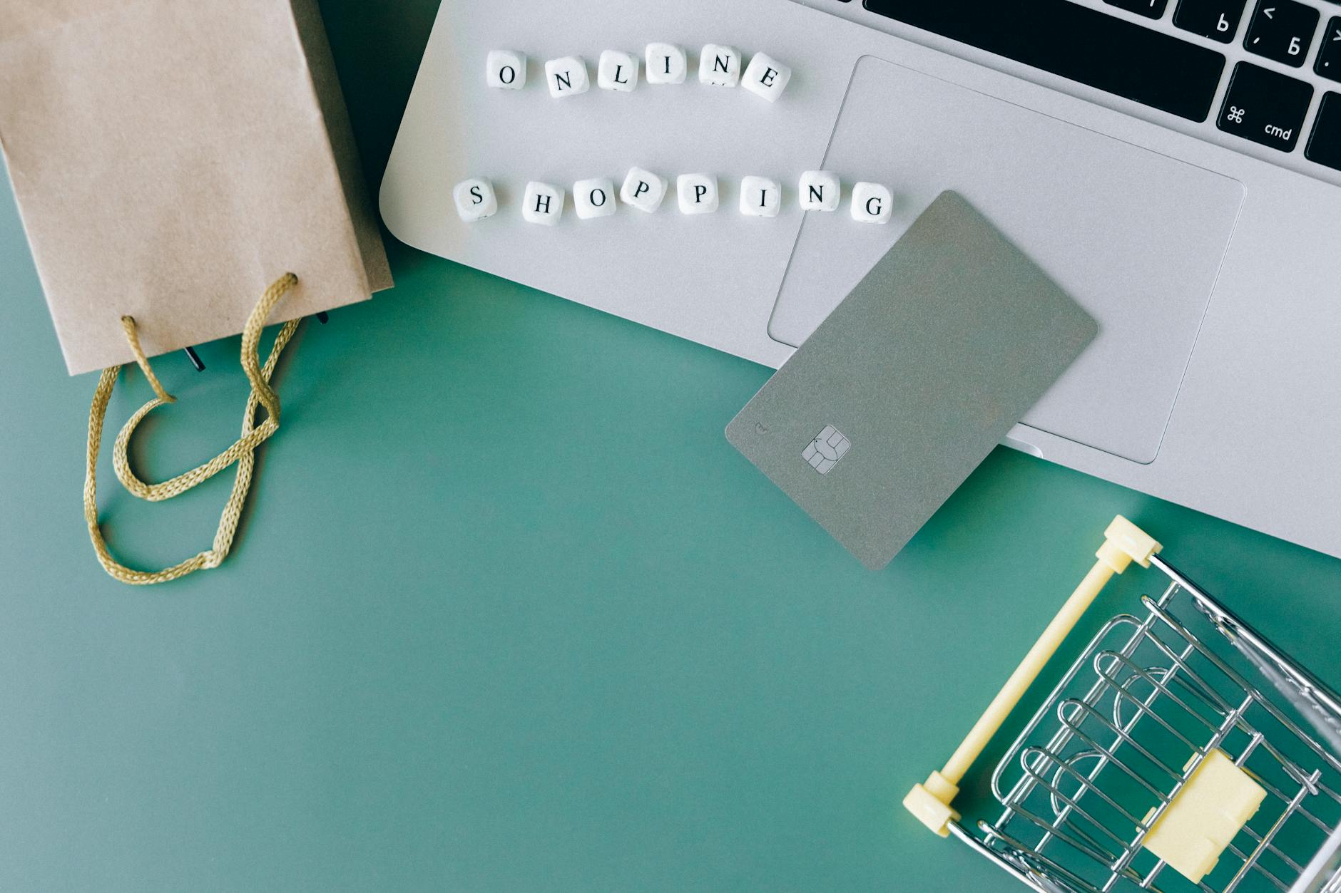 Laptop, karta płatnicza i mini wózek jako symbol zakupów online