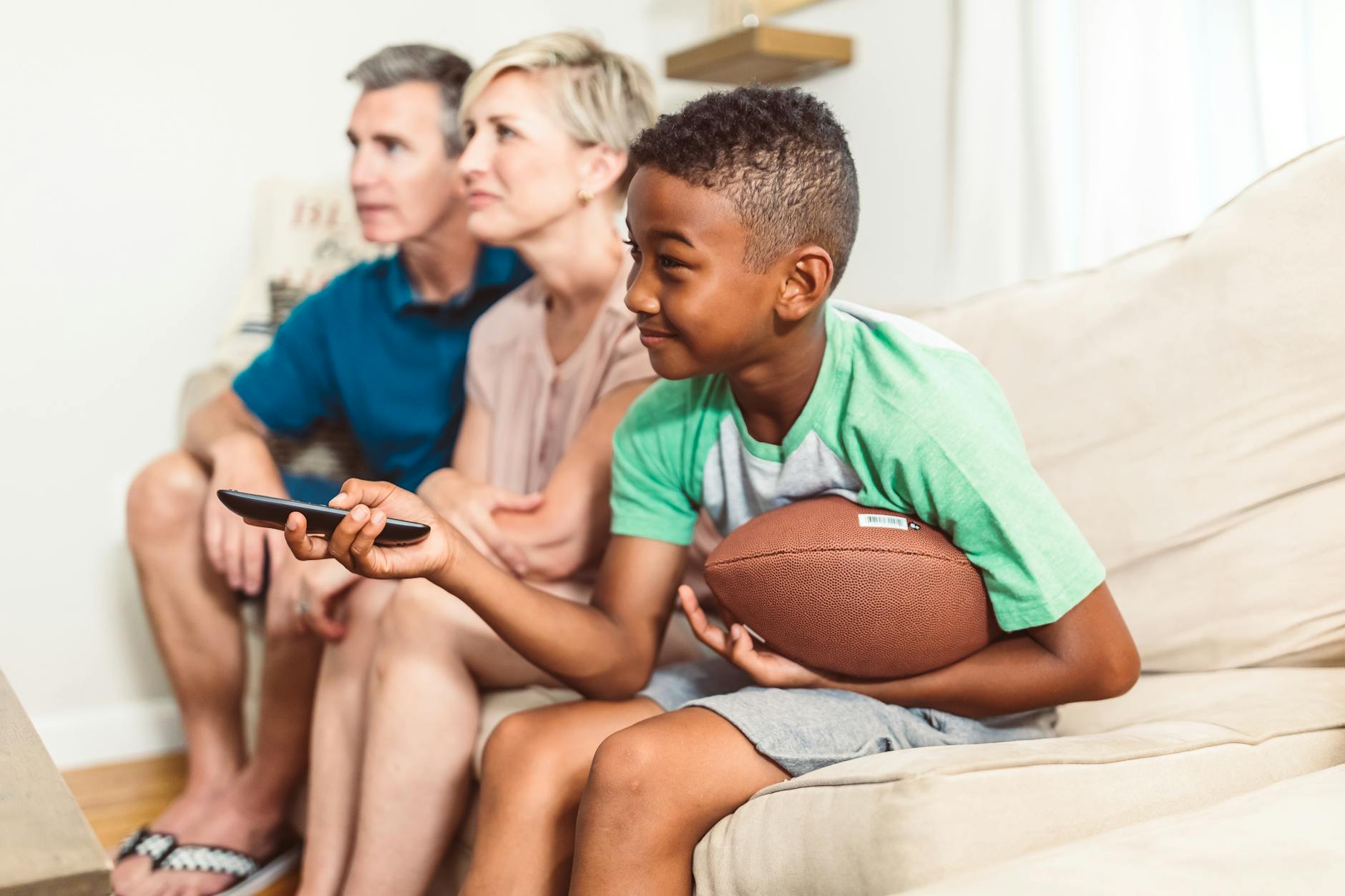 Rodzina na kanapie ogląda nowoczesny telewizor w salonie