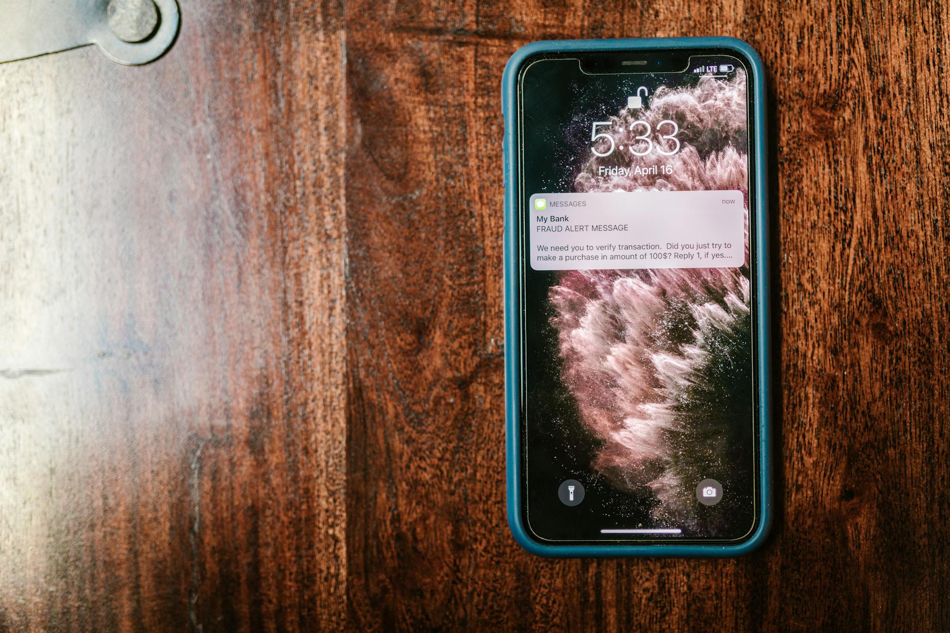 Smartfon na stole z wyświetlonym ostrzeżeniem o oszustwie